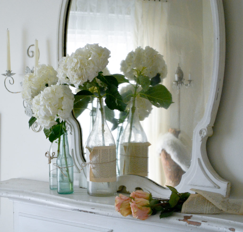 hydrangeas in glass bottles,antique mirror, dress form, antique mantel