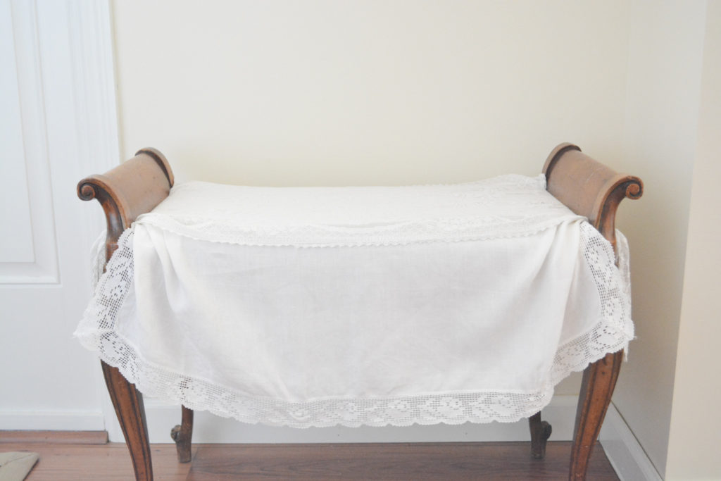 french bench draped with vintage linens