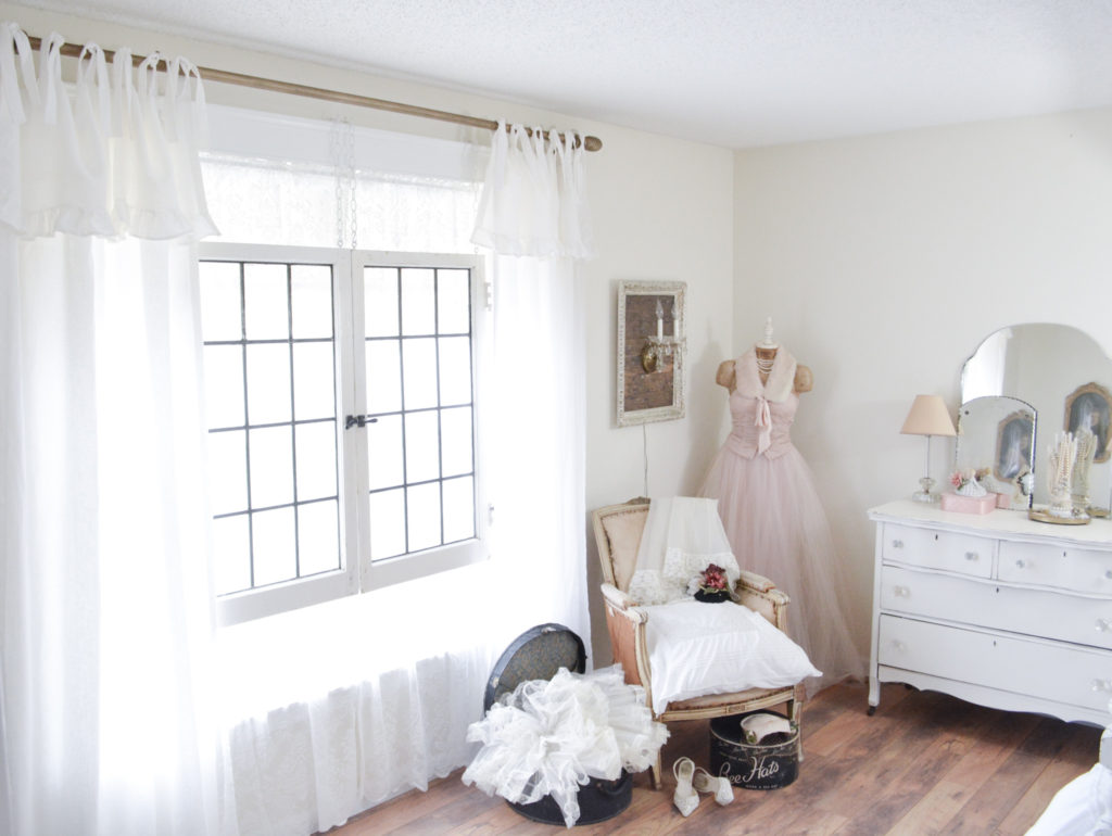 Romantic cottage style bedroom with tie top curtains and DIY antique brass curtain rod.