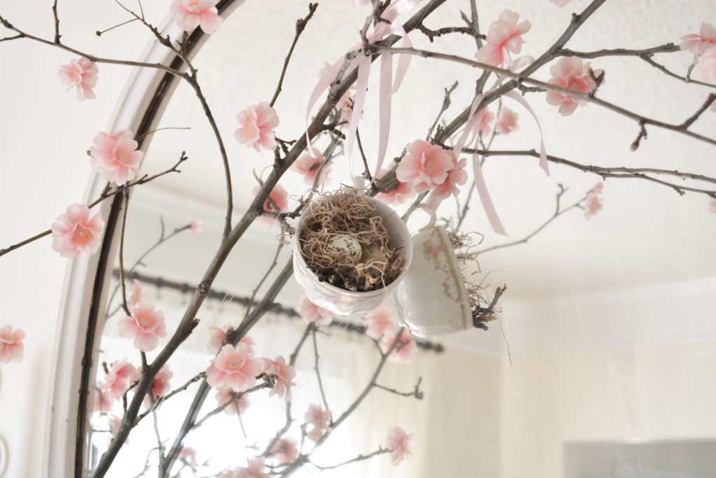 Spring flowering branch on antique fireplace mantel with tea cup birds nest