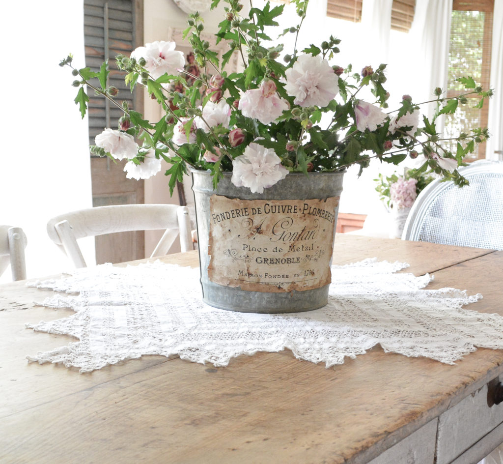 An Antique farm table with bucket of fkowers