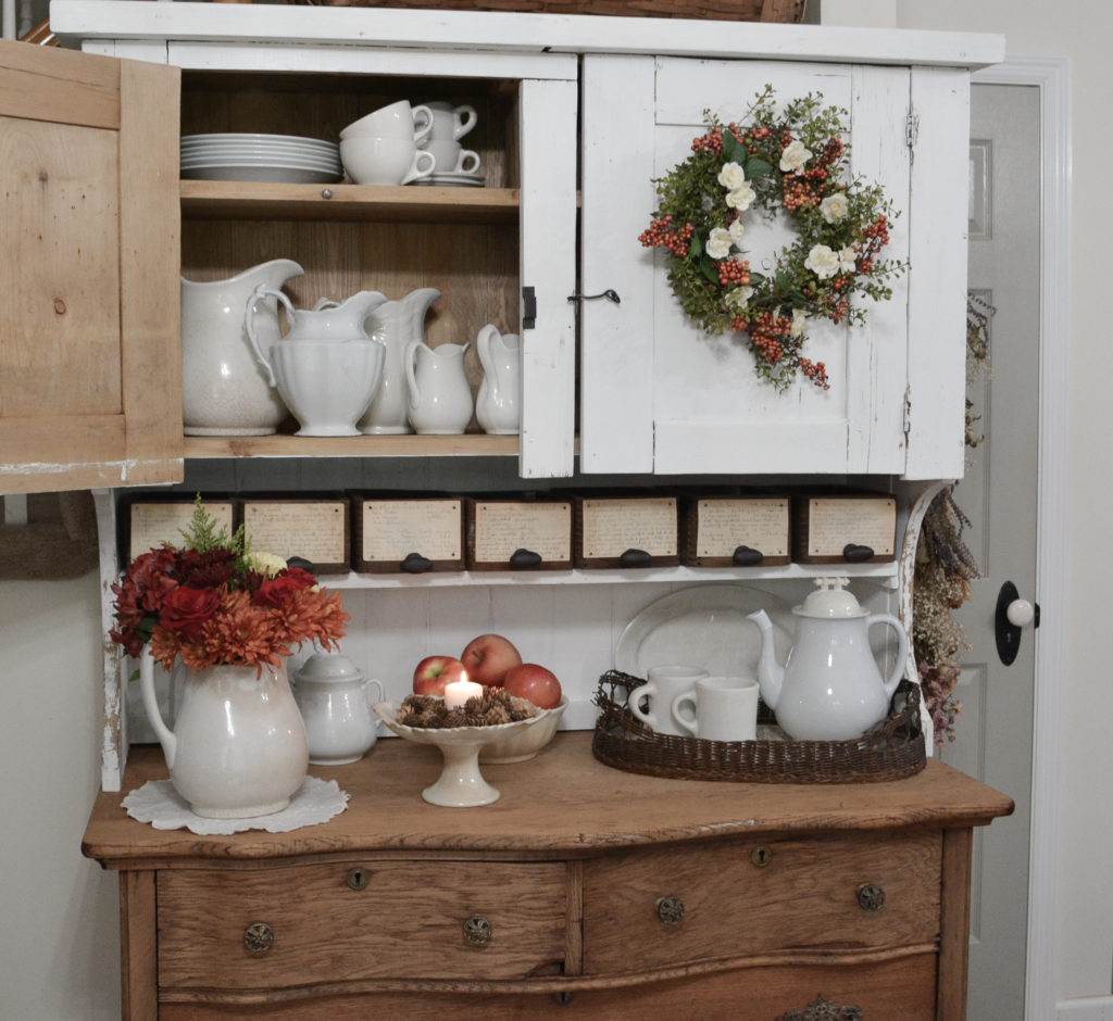 White hutch top on old buffet filled with ironstone