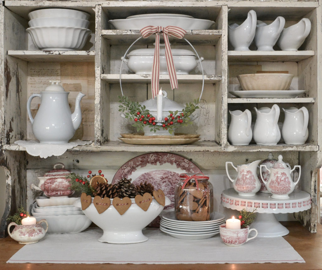 a diy hanging candle ring for Christmas hanging on a hutch filled with ironstone and red and white dishes