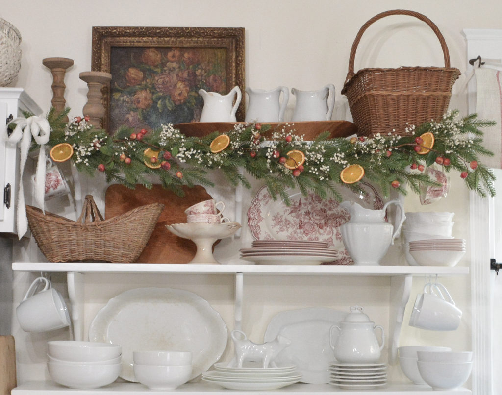 dried orange slice garland on a shelf with red and white dishes