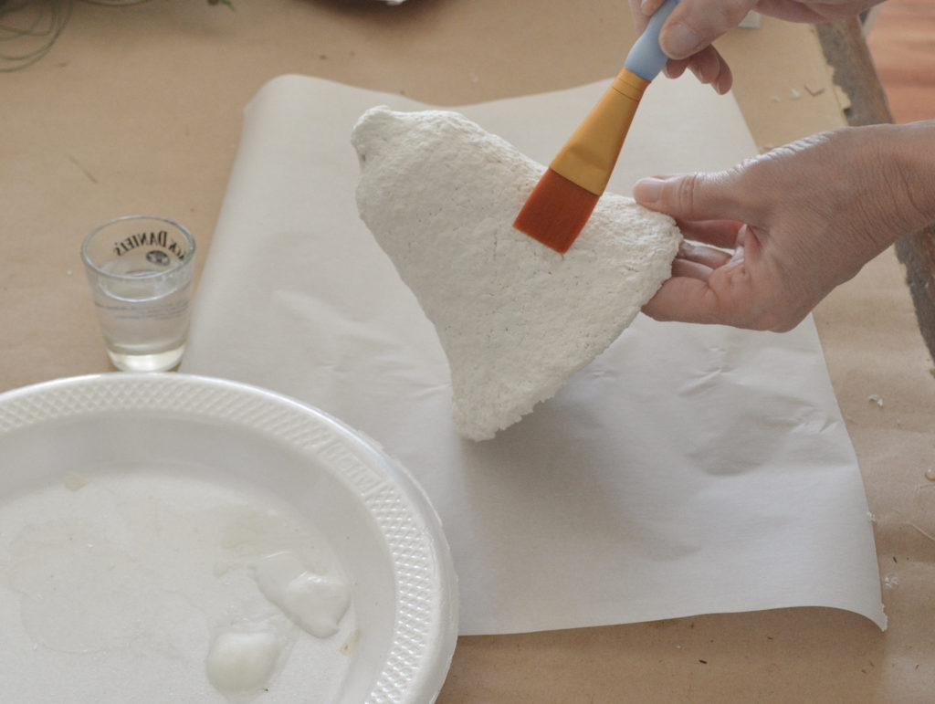 applying glue to a paper mache bell