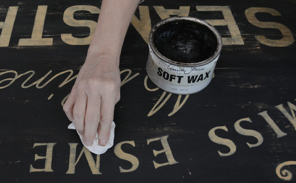 applying dark wax to a DIY sign