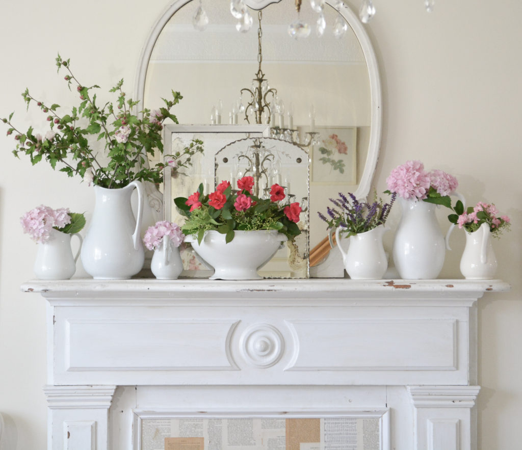white cottage fireplace mantel and fresh flowers in white pitchers