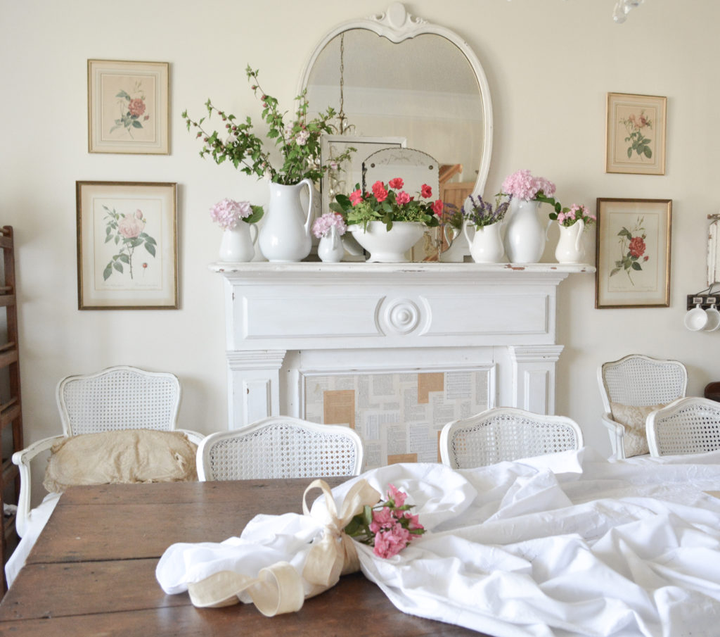 antique fireplace mantel with fresh flowers behind a farm table with white tablecloth and flowers