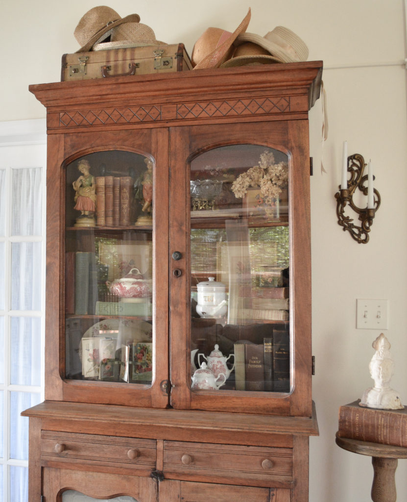 An antique china cabinet decorated English cottage style