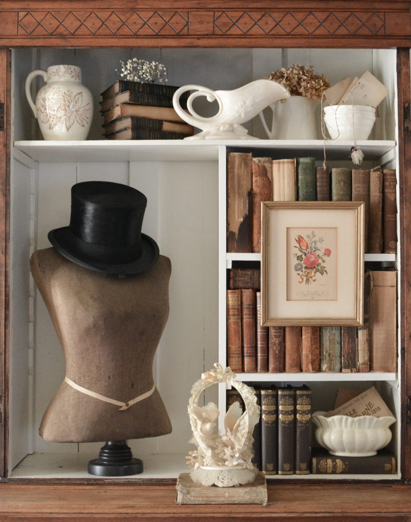 I turned a china cabinet into a display case and filled it with antique books and an antique mannequin bust