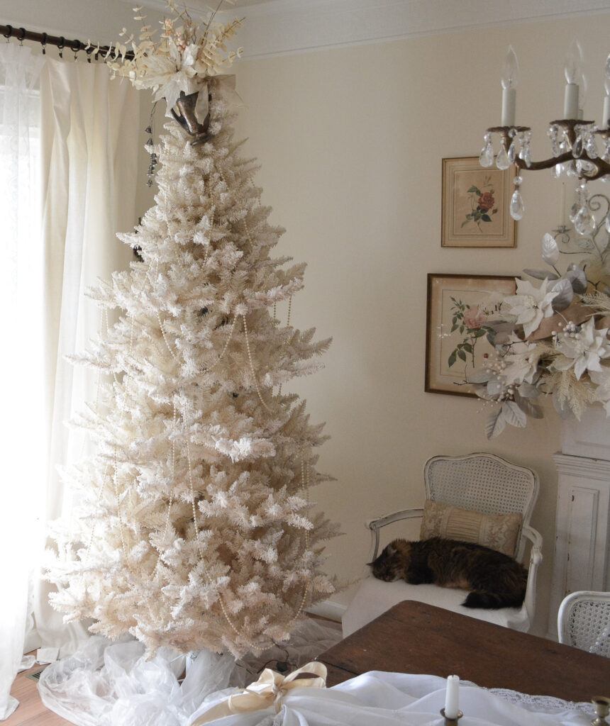 Adding pearl bead garland to an antique white Christmas tree