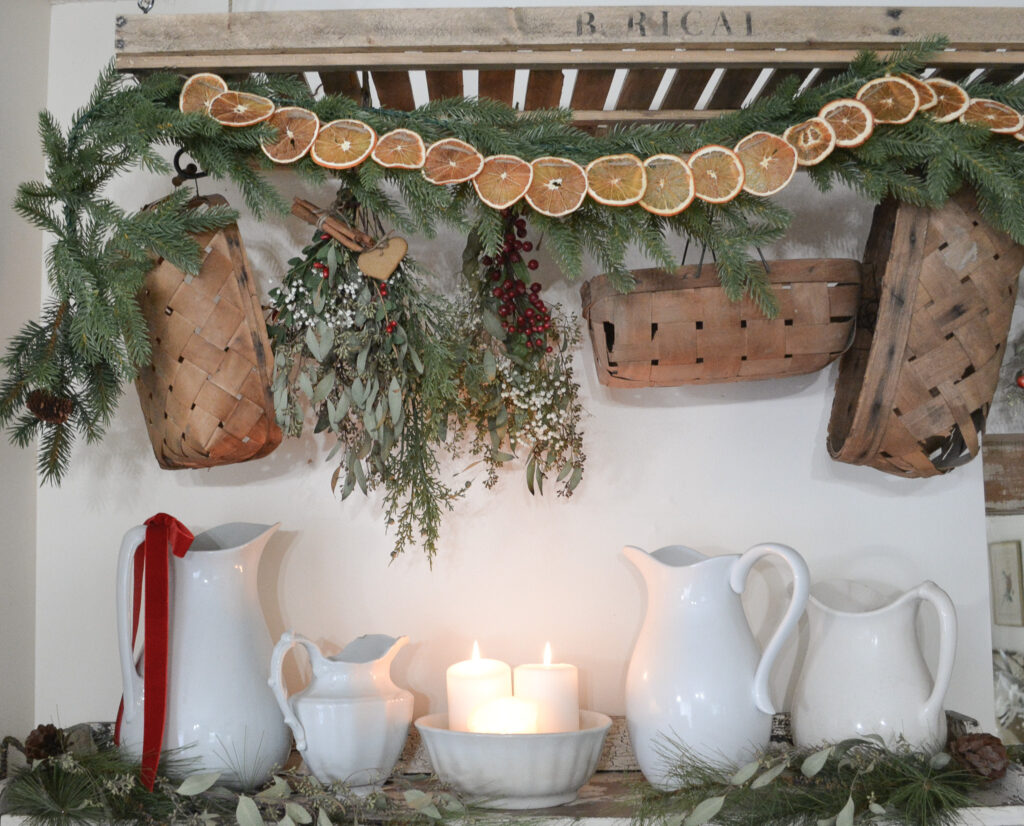 baskets and orange slice garland hang from a rustic drying rack over ironstone pitchers