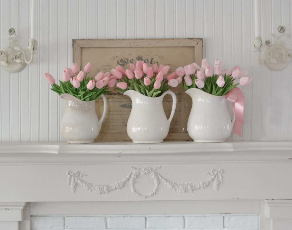 fireplace mantel with three pitchers of tulips